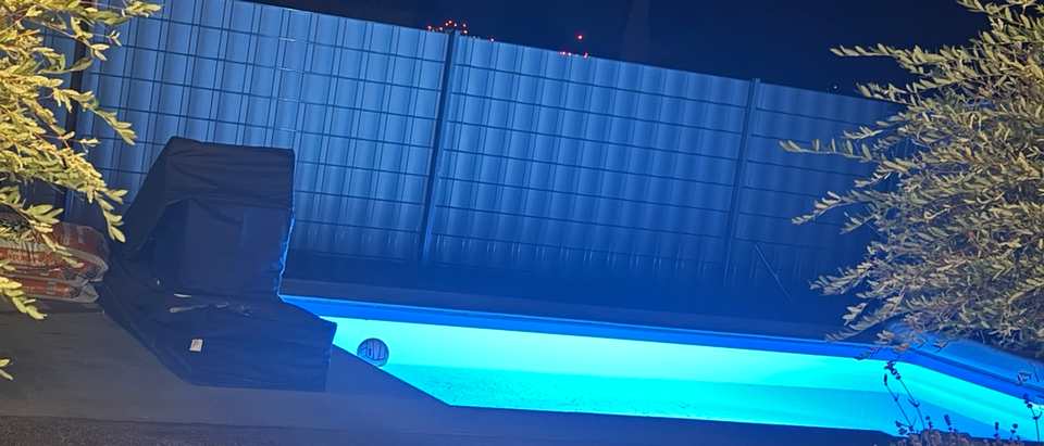 Fertiggestellter und beleuchteter Pool mit gepflasterter Umrandung in Calden bei Nacht